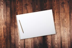A notepad laying on a dark wooden surface.